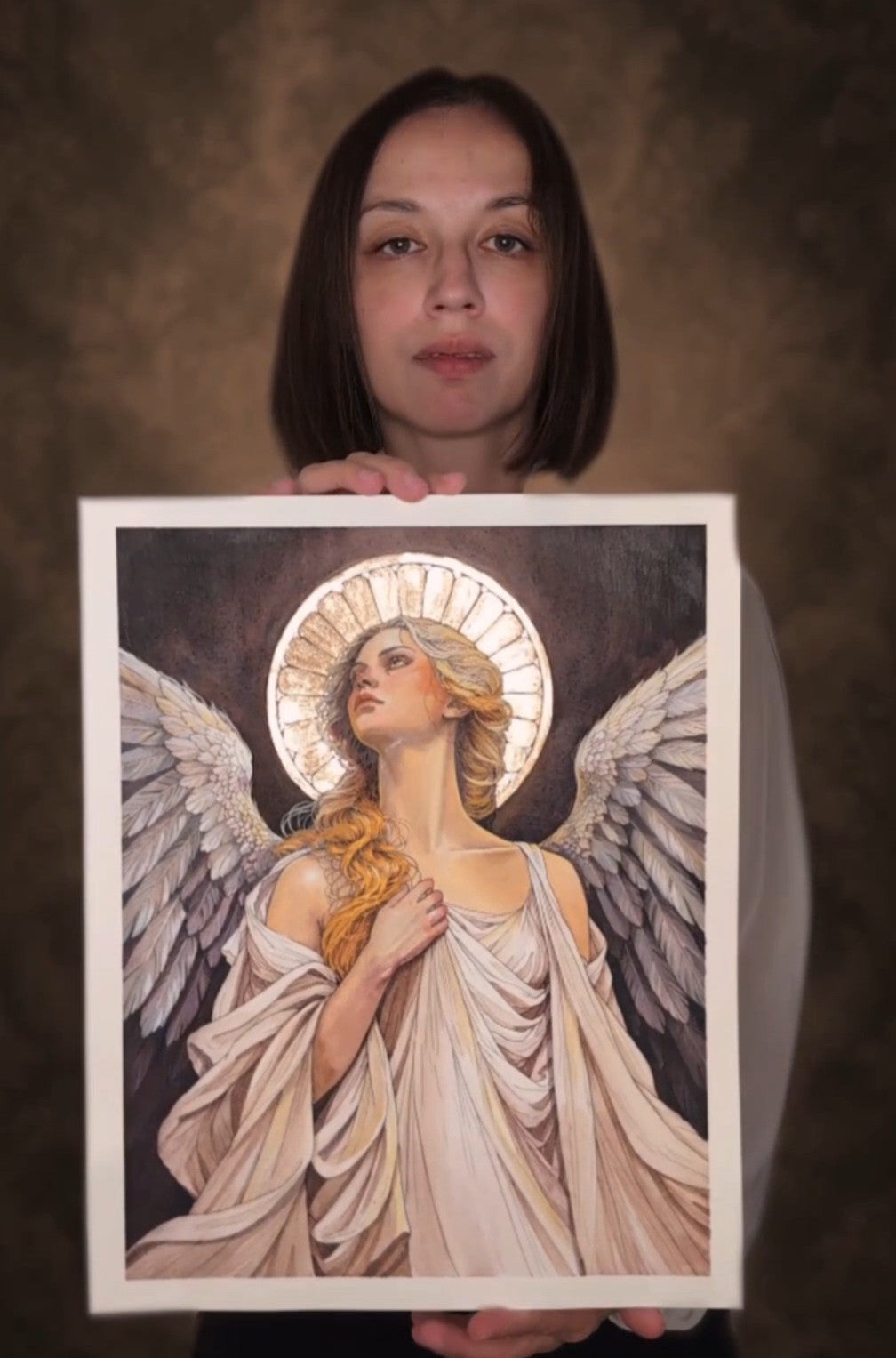 Artist Manuela De Simone holding her original painting The Angel Who Stayed, showing the artwork and its scale.